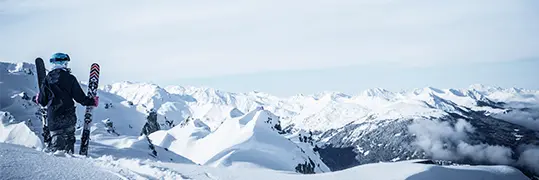 un skieur qui contemple un panorama de montagnes enneigées